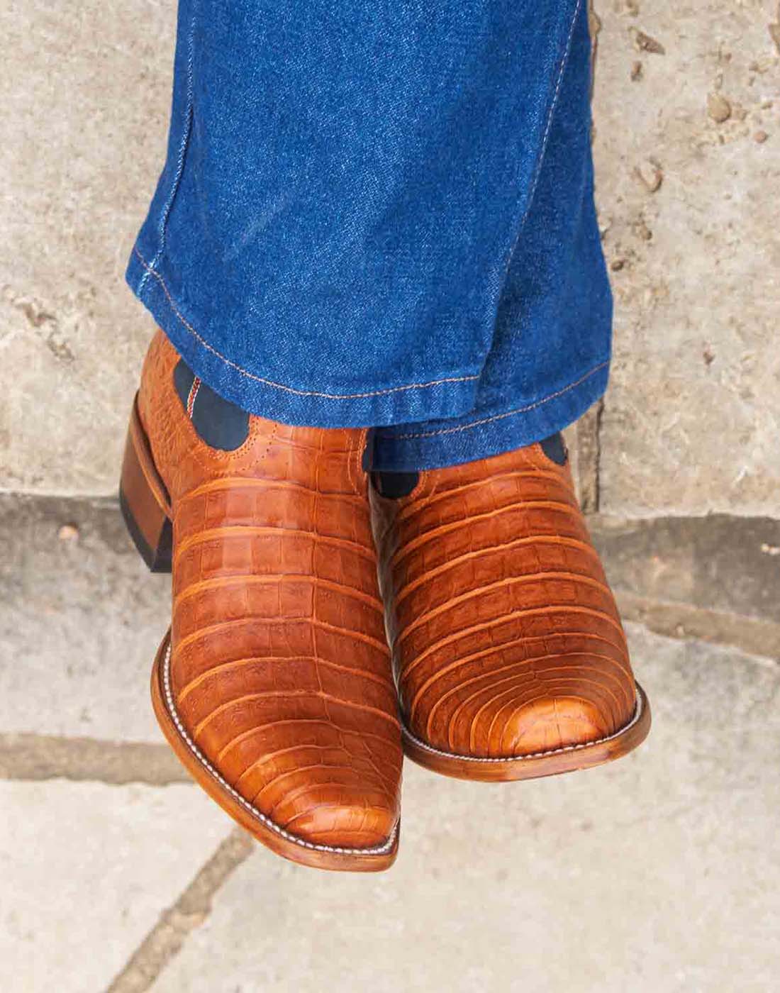 Close-up image of man wearing a pair of RUJO caramel caiman cowboy boots