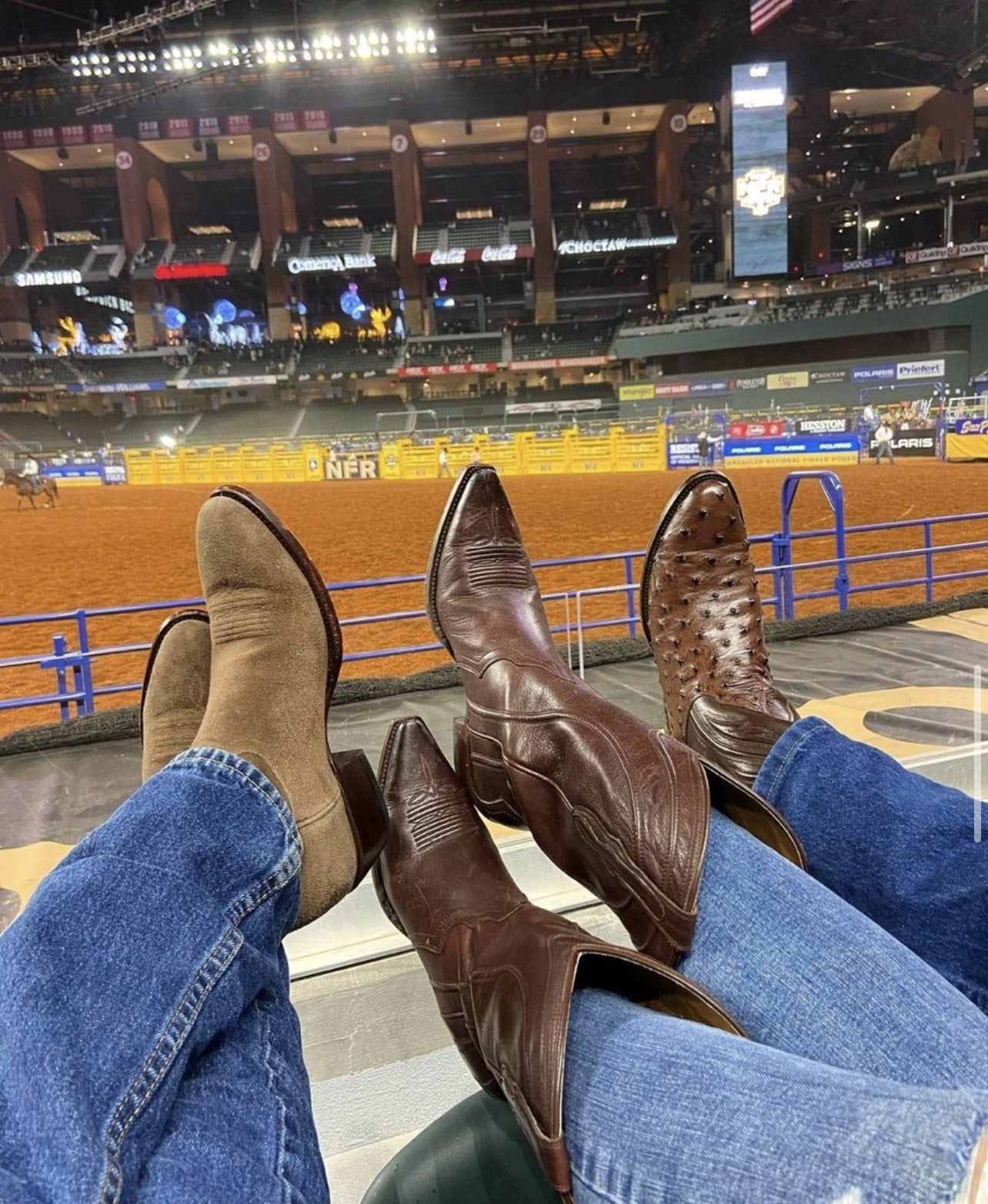 a small group of people at the rodeo showing off their RUJO boots by resting them on a fence.
