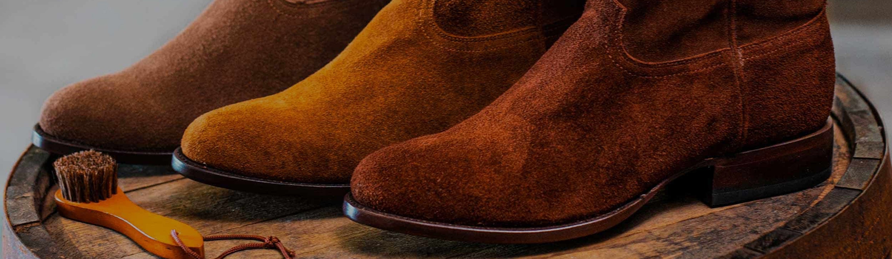 Close-up of RUJO's Sentry Suede cowboy boots sitting on a barrel
